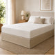 Cache sommier à coins fendus beige installé sur un lit