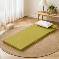Matelas de sol coin lecture vert olive, deplie sur un tapis en jute avec oreiller blanc et livres