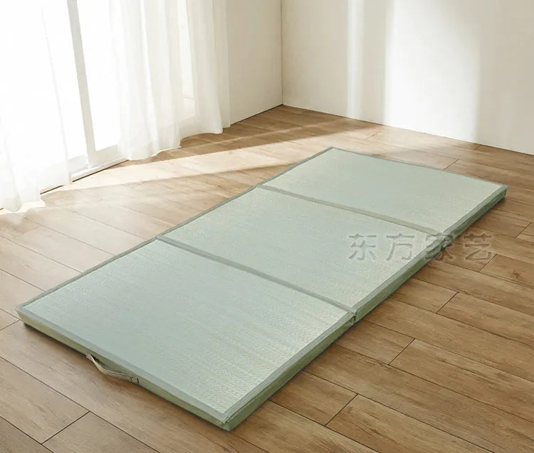 Natte tressée vert clair pliée en trois, posée sur un parquet