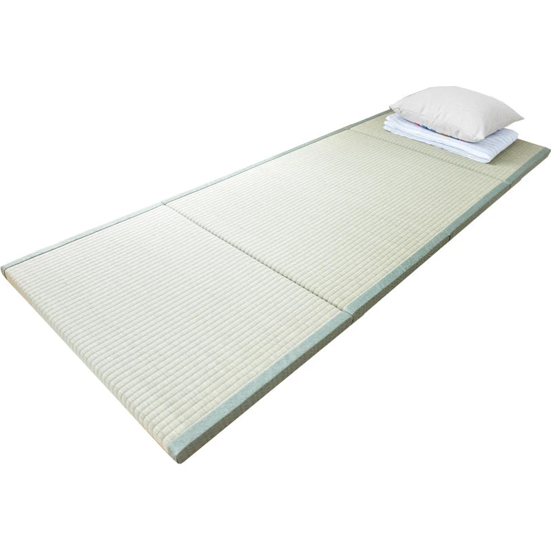 Natte tressée vert clair avec linge de lit plié et oreiller, sur fond blanc