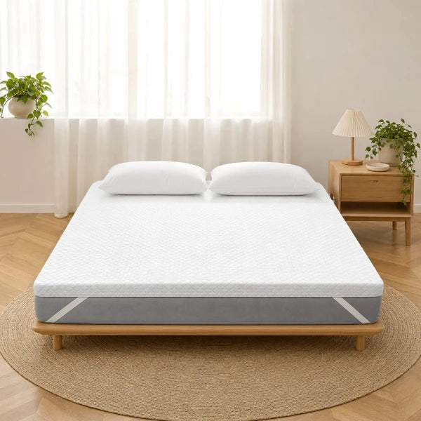 Surmatelas en gel blanc posé sur un lit dans une chambre, matelassage en vagues, oreillers blancs