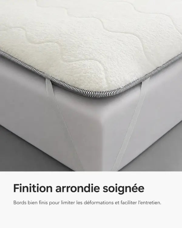 Coin du surmatelas blanc avec finition arrondie soignée et sangles élastiques