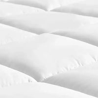 Gros plan sur le matelassage en carrés du surmatelas en plume