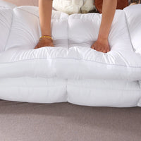 Mains ajustant le surmatelas épais matelassé sur un lit