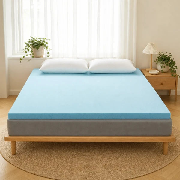 Surmatelas mémoire de forme bleu posé sur un lit, matelas gris visible, deux oreillers blancs