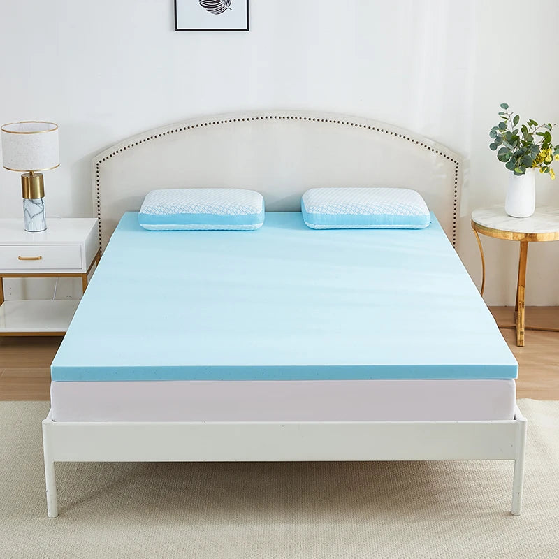 Surmatelas mémoire de forme bleu posé sur un lit à tête de lit capitonnée blanche, vue large de la chambre