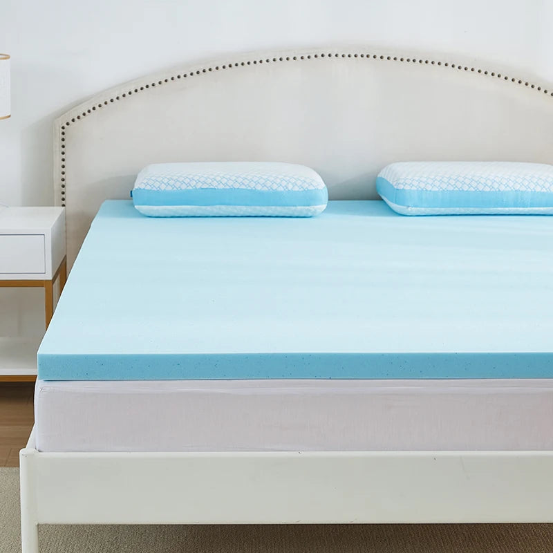 Surmatelas mémoire de forme bleu posé sur un lit, gros plan sur les oreillers et la tête de lit capitonnée