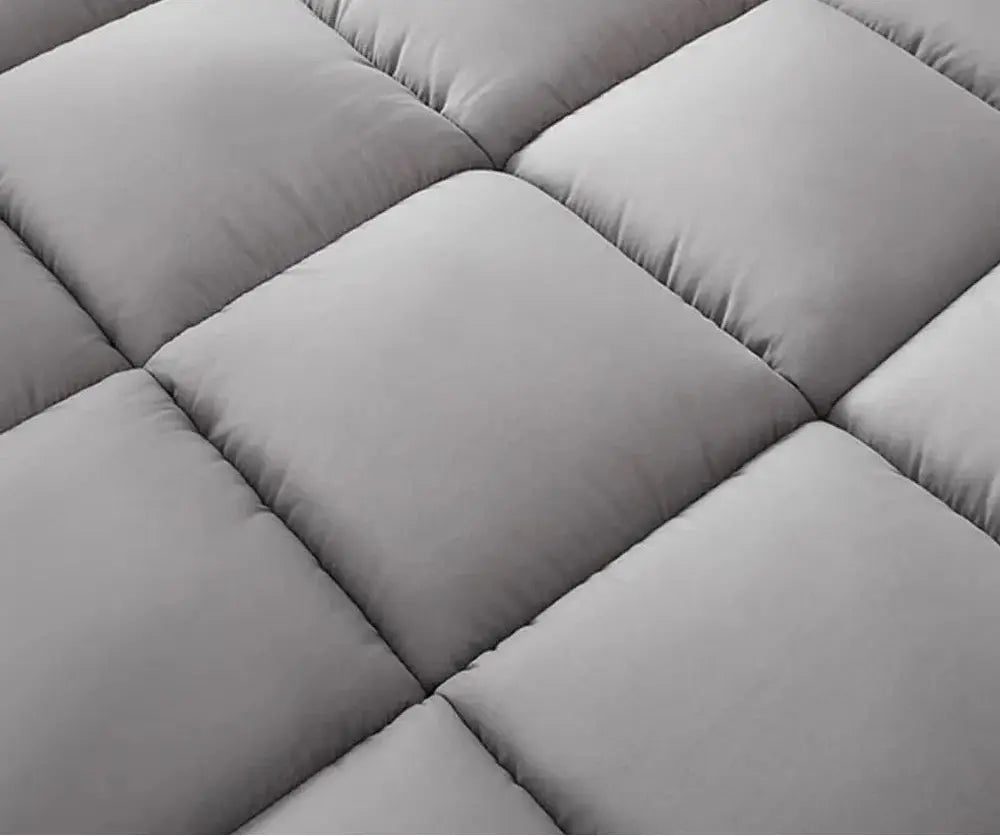 Gros plan sur le matelassage en carrés du topper gris